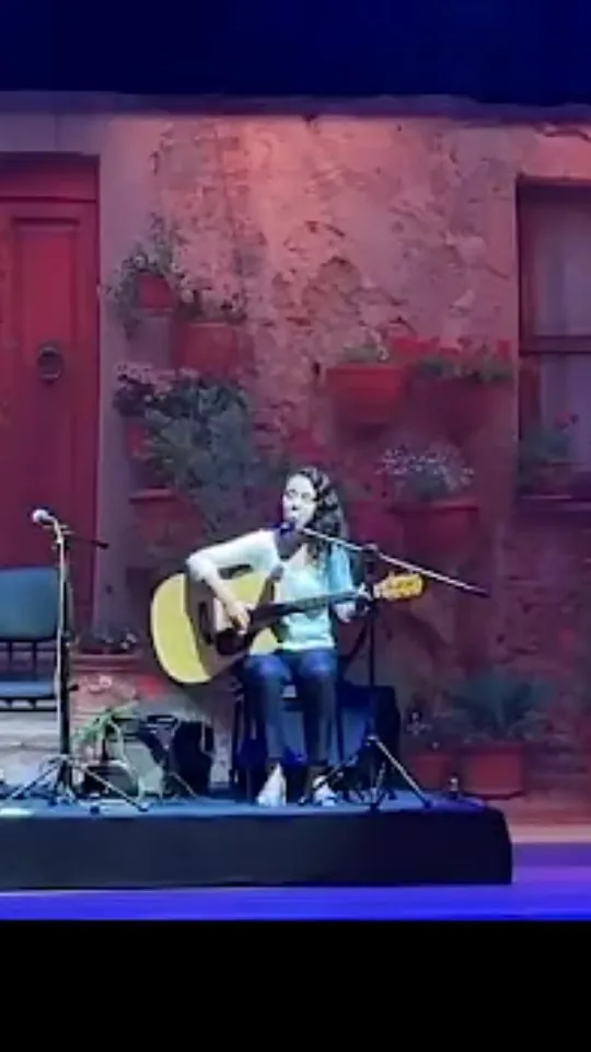 Victoria tocando violão em cena de teatro