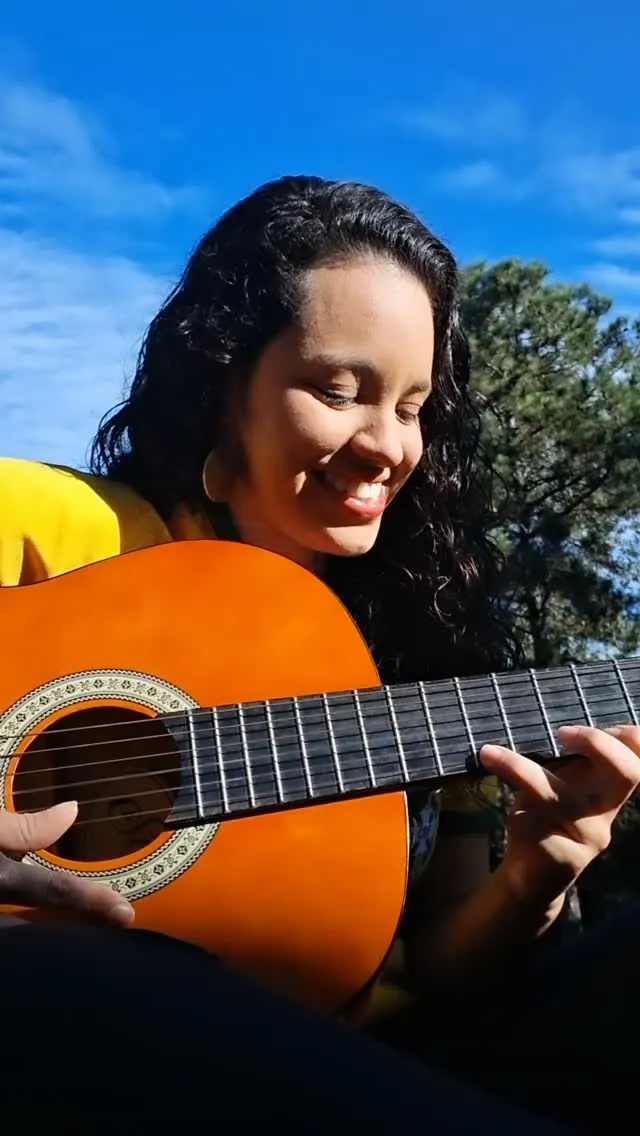 Victoria tocando violão sob o sol
